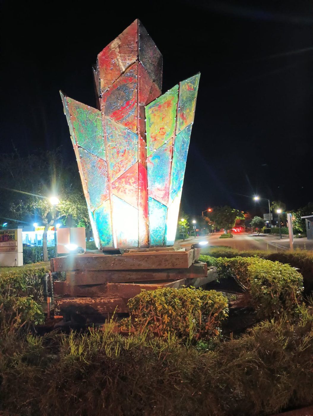 Outdoor sculpture lit from below with colored architectural lighting at night