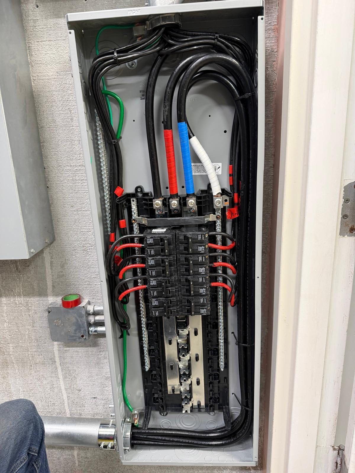 Interior of a commercial electrical panel with color coded feeders and neat terminations