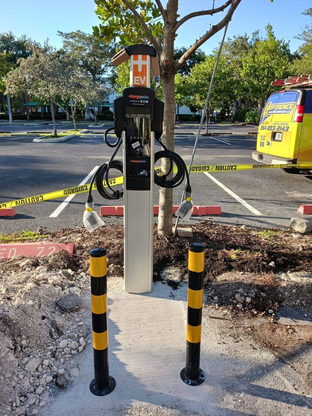 Dual port electric vehicle charging station with protective bollards in a commercial parking lot