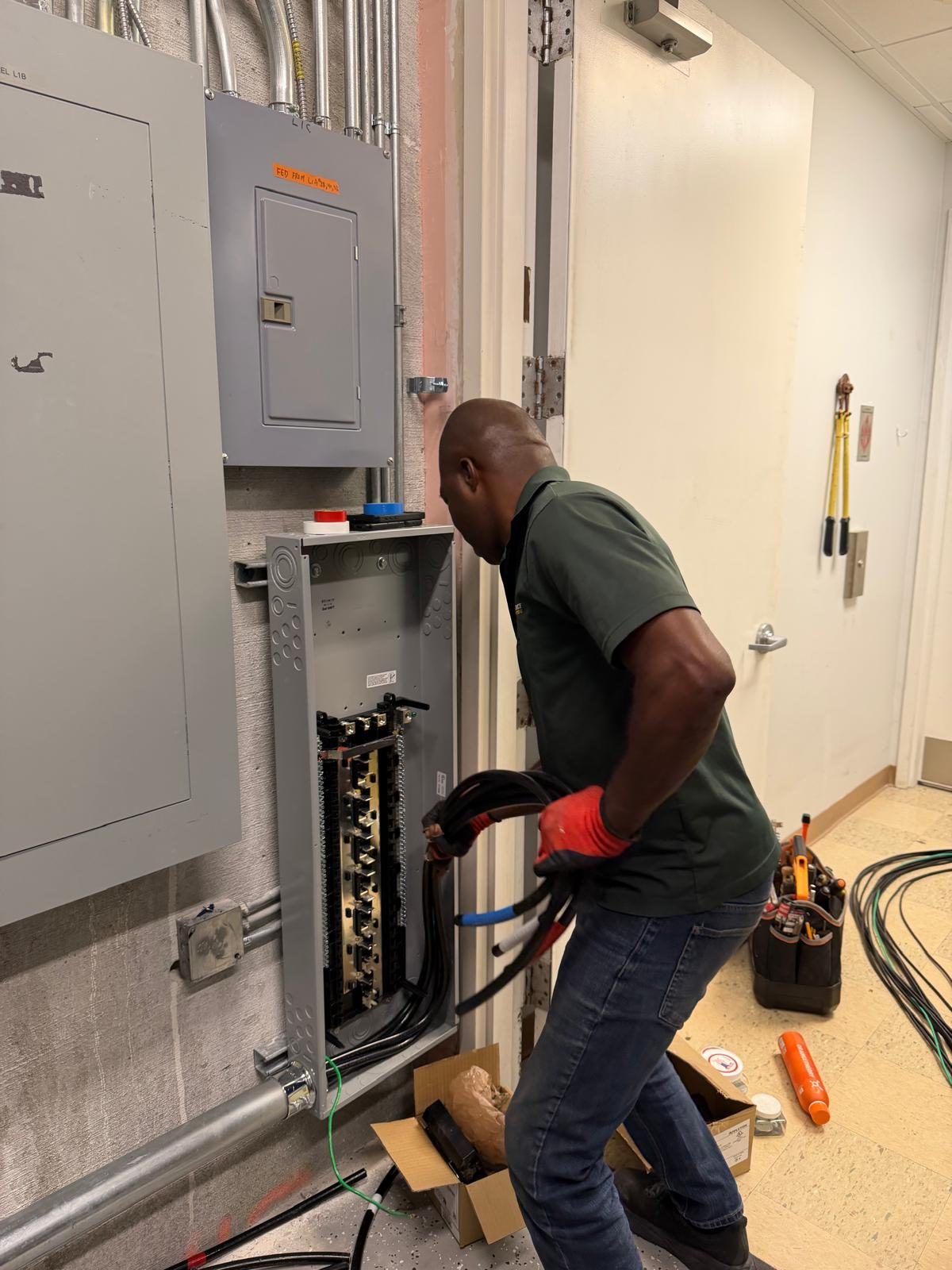 A Reference Electric technician pulling feeder cable into a commercial panel