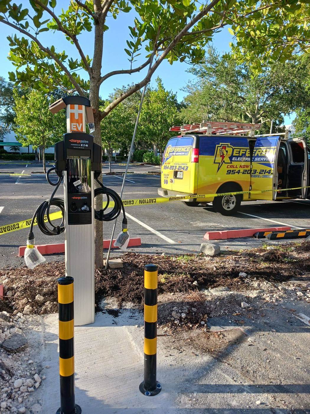 Electric vehicle charging station in a parking lot with the work area taped off and a service van nearby