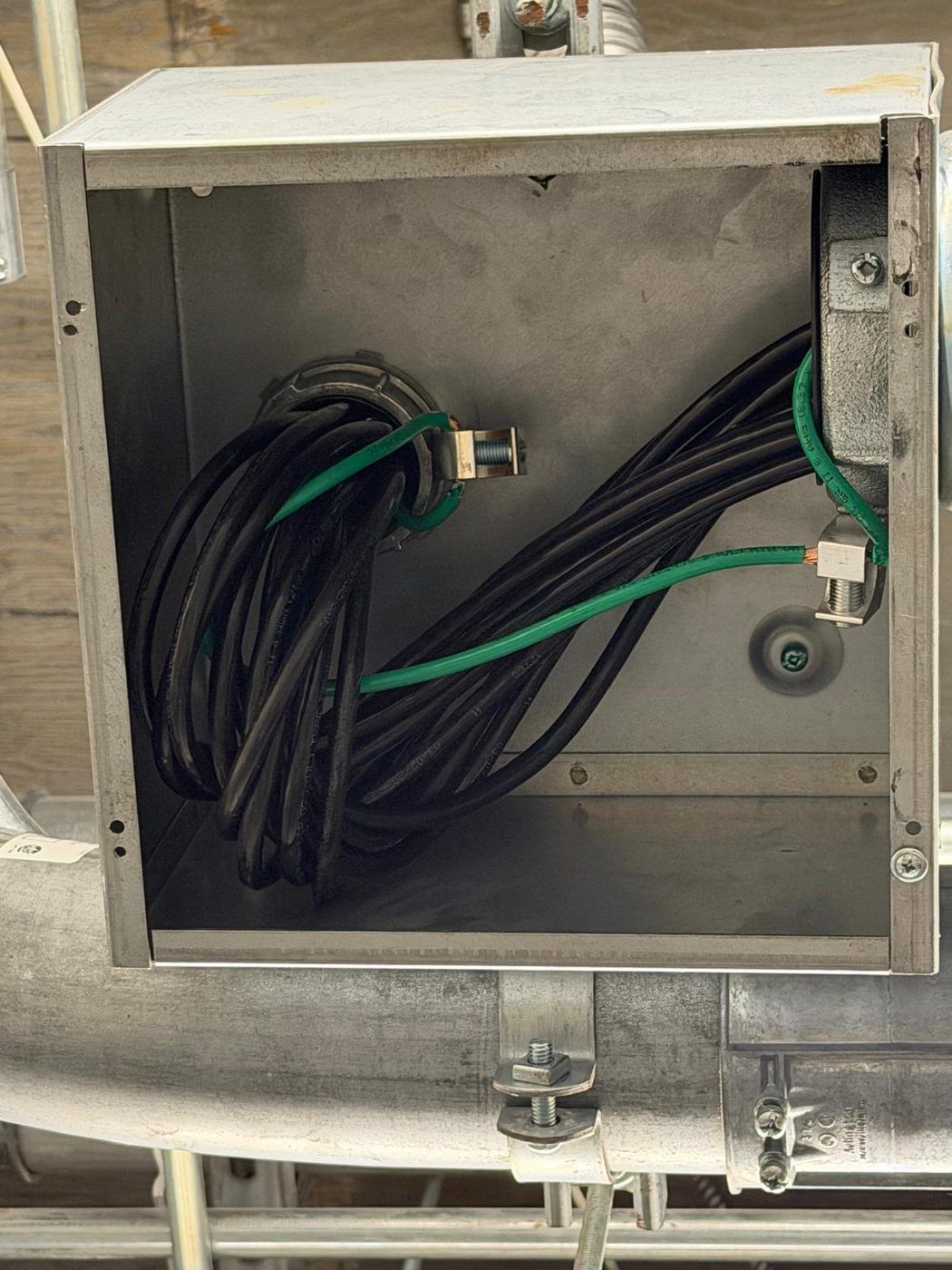 Junction box interior showing grounding and bonding conductors landed on lugs